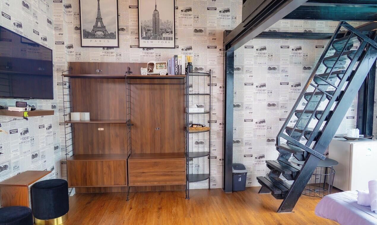 Una habitación moderna con un armario de madera, un escritorio con silla, una estantería y una escalera.