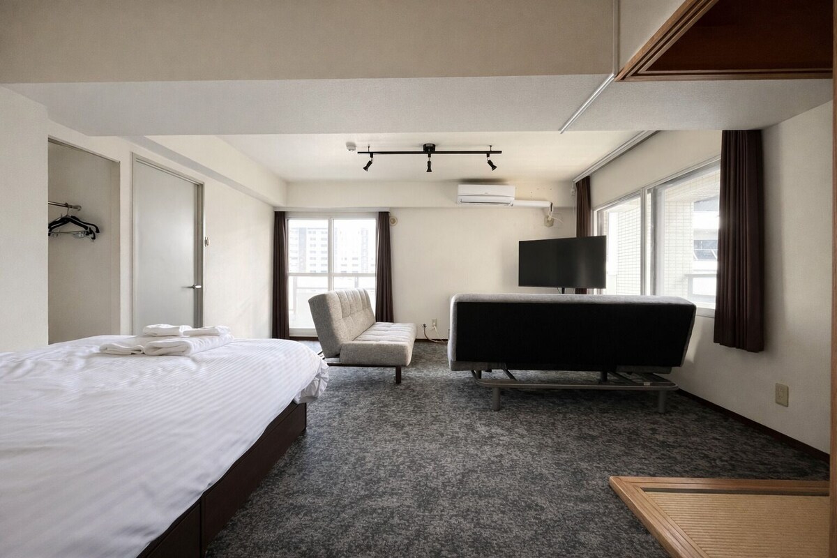 Una habitación de hotel con cama, sofá, televisión y ventana.