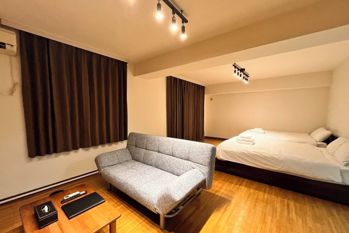 A hotel room with a sofa, a bed, a desk, and a chair.