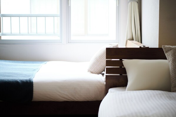Une chambre d’hôtel avec deux lits, une fenêtre avec des rideaux et une tête de lit en bois.