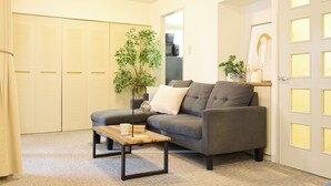 A living room with a grey sofa, a wooden coffee table, a plant, and a door with frosted glass panels.