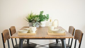 A dining table set with white dishes and a tray, surrounded by chairs.