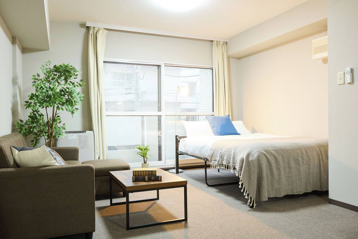 A modern hotel room with a bed, sofa, and a small table.