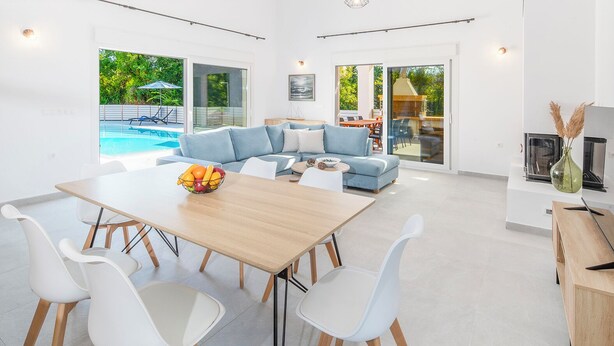 Ein großzügiger Wohnbereich mit Pool, einem Esstisch mit Stühlen und einer Couch.