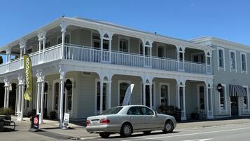 A two-story building with a balcony on the upper floor, a sign that reads 'BOOKSHOP,' and a parked car in front.