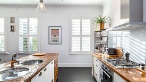 A modern kitchen with white cabinetry, a wooden countertop, a gas stove, and a sink. - Altitude Apartment Stylish Village Apartment | 2BR, Balcony & Prime Location (Martinborough)