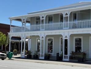 A two-story building with a balcony, storefronts, and potted plants. - Altitude Apartment, Martinborough (Martinborough)