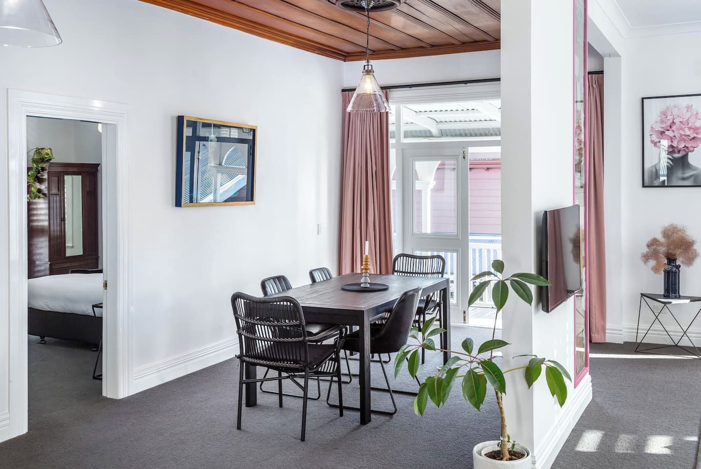 A dining area with a table and chairs, a hanging light fixture, and a potted plant.