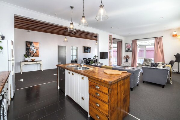 A modern kitchen with a central island, pendant lighting, and a dining area with a sofa and table.
