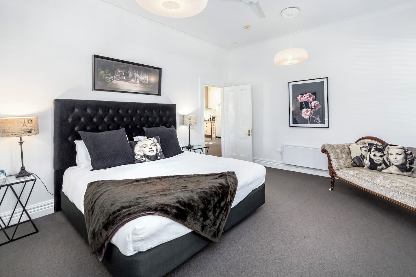 A hotel room with a large bed, a sofa, a desk, and a mirror.