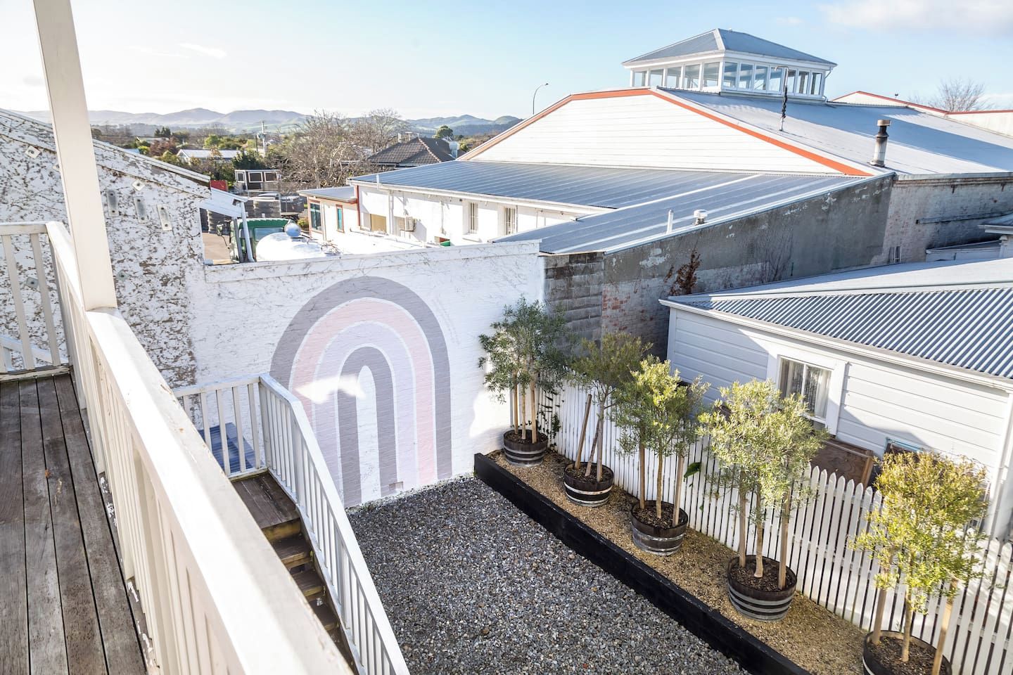 A residential area with a white building, a solar panel roof, and a white picket fence.