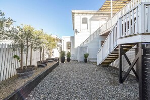 A courtyard with a gravel path, potted plants, a white fence, and a building with a staircase. - Altitude Apartment, Martinborough (Martinborough)