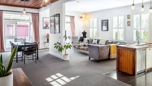 A spacious living area with a dining table, chairs, a sofa, and a kitchen island. - Altitude Apartment Stylish Village Apartment | 2BR, Balcony & Prime Location (Martinborough)