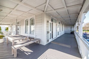 A covered porch with a wooden deck, white railings, and a bench. - Altitude Apartment, Martinborough (Martinborough)