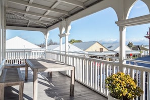 A covered wooden deck with a railing, a bench, and a potted plant. - Altitude Apartment, Martinborough (Martinborough)