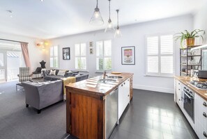 A spacious living area with a large sofa, a dining table, and a kitchen with a wooden island.