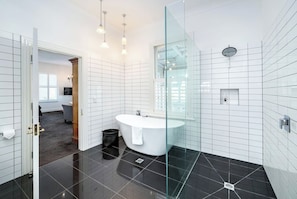 A modern bathroom with a freestanding bathtub, a glass shower enclosure, and a visible toilet paper holder. - Altitude Studio Apartment (Martinborough)