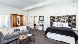 Ett modernt sovrum med en grå soffa, en svart säng och ett litet sidobord.