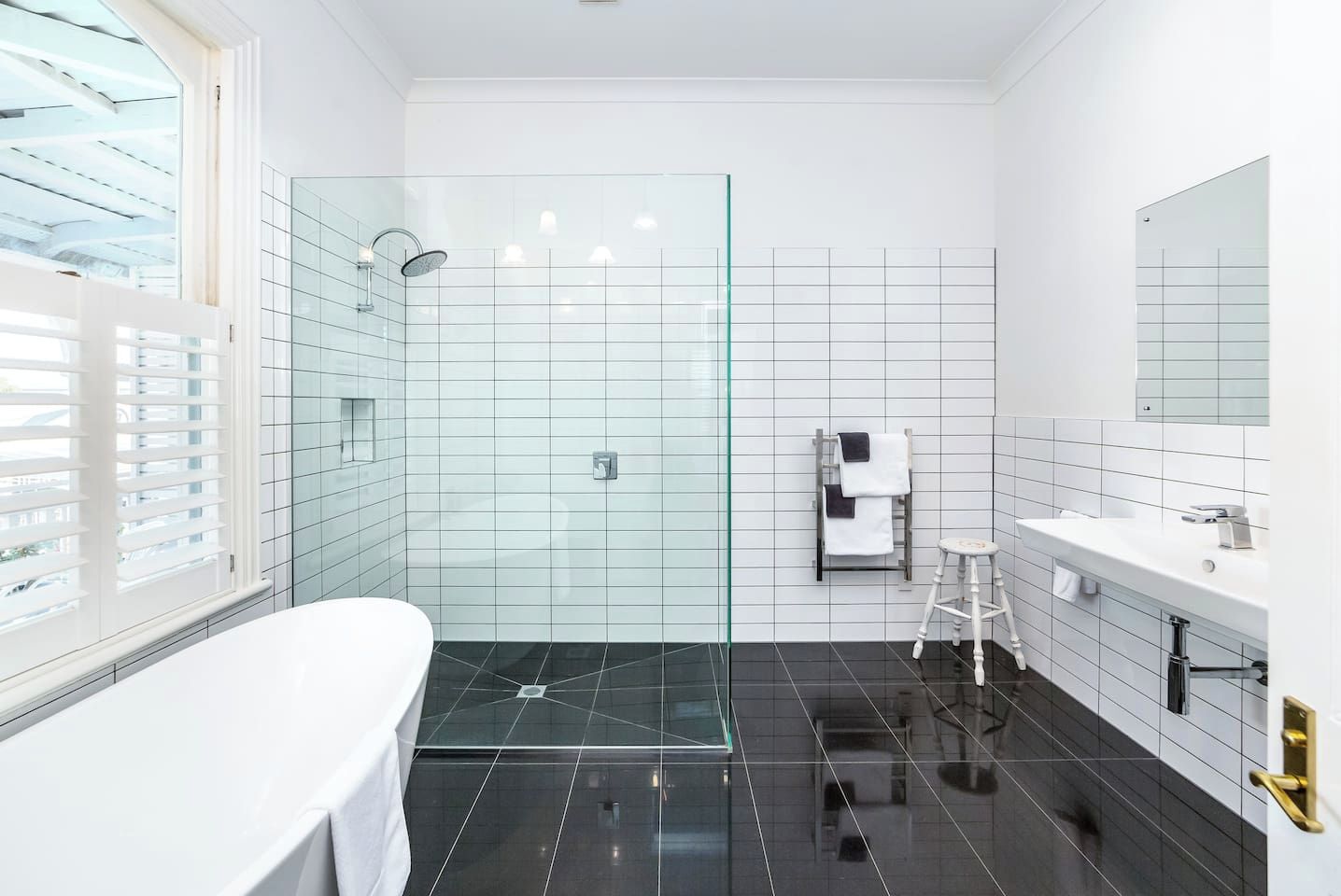 A modern bathroom with a glass-enclosed shower, a white bathtub, and a vanity with a mirror.