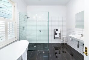 A modern bathroom with a glass-enclosed shower, a white bathtub, and a vanity with a mirror. - Altitude Studio Apartment (Martinborough)