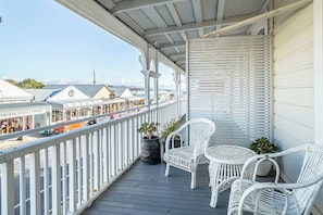 Ein Balkon mit weißen Korbstühlen und einem Blumentopf.