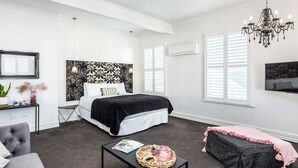 A bedroom with a bed, bedside table, and a TV mounted on the wall. - Altitude Studio Apartment (Martinborough)