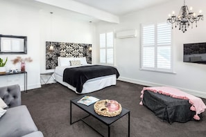 Ein Schlafzimmer mit einem Bett, einem Nachttisch und einem an der Wand befestigten Fernseher.