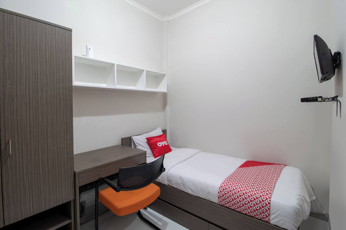 Ein Schlafzimmer mit Bett, Schreibtisch, Stuhl, Kleiderschrank und einem Wand-Fernseher.