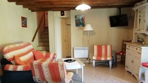 Un salon chaleureux avec un canapé à rayures, une petite table, une lampe et un téléviseur fixé au mur.