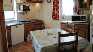 Une cuisine compacte équipée d’un lave-vaisselle, d’un four à micro-ondes et d’une table à manger avec des chaises.