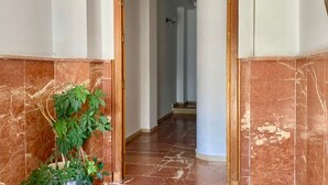 Un pasillo con piso de mármol y marco de puerta de madera.