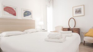 Habitación de hotel con una cama grande, una mesita de noche, una silla, un espejo y obras de arte en la pared.