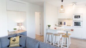 Una cocina moderna con armarios blancos, una isla central con taburetes y una lámpara colgante.