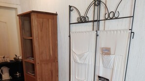 A wooden cabinet with drawers, a metal rack with hanging items, and a tiled floor. - Belle Suite Avec Coin Cuisine Dans Maison Périgourdine (Plazac)