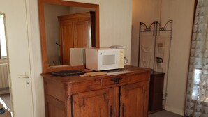 A wooden cabinet with a microwave on top, a mirror above it, and a door to the left. - Belle Suite Avec Coin Cuisine Dans Maison Périgourdine (Plazac)