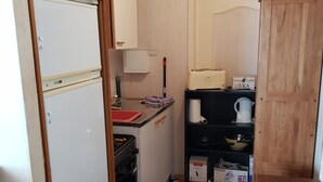 A compact kitchen with a refrigerator, stove, and a small countertop with various items. - Belle Suite Avec Coin Cuisine Dans Maison Périgourdine (Plazac)