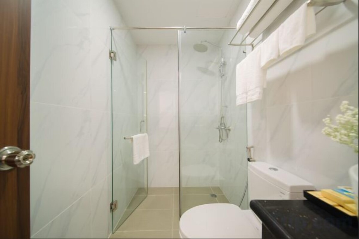 A glass-enclosed shower stall with a toilet and a sink area.