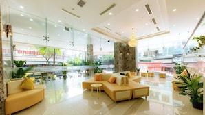 A spacious lobby with a large beige sectional sofa, a small round table, and a chandelier. - The Gold Coast Hotel Nha Trang (Nha Trang)