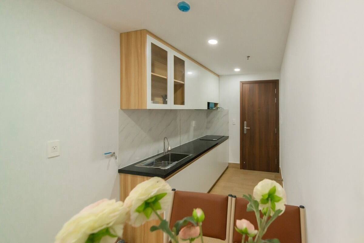 A compact kitchen with a built-in oven, a sink, and a wooden cabinet above the countertop.