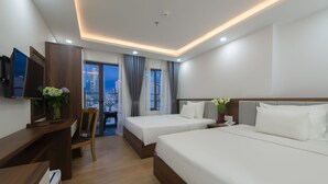 Quarto de hotel com duas camas, uma mesa, uma cadeira e uma televisão.