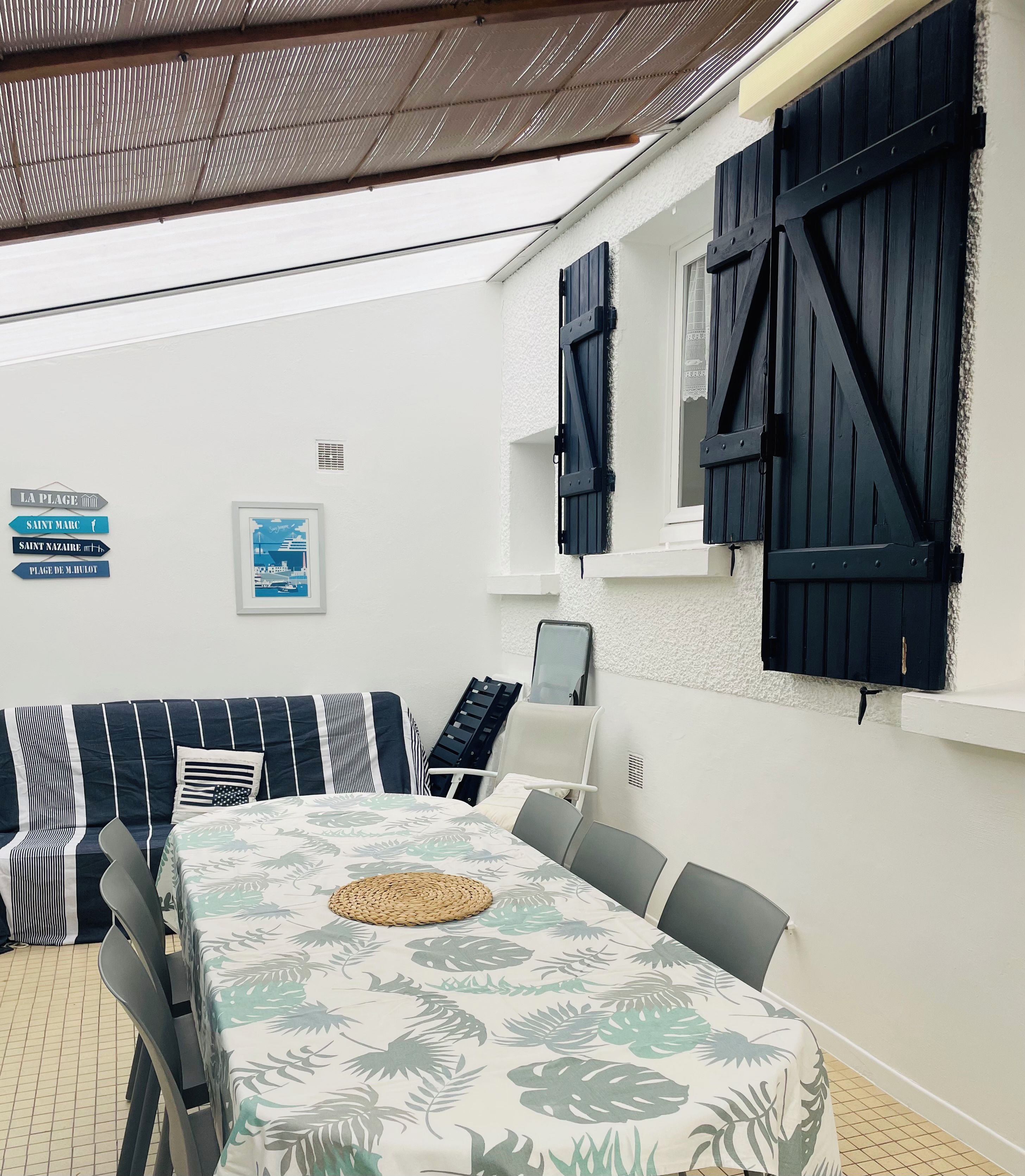 Een kamer met een eettafel, stoelen, een bank en uitzicht op zee.