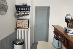 Eine Küche mit einem Holzkasten, einer Wanduhr und einer Tür.