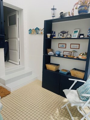 A room with a white door, a dark blue bookshelf, and a tiled floor.