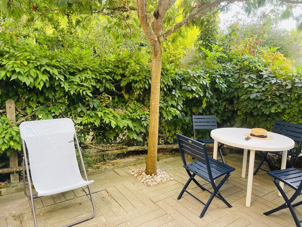 Eine Außenpatio mit einem runden Tisch, vier Stühlen und einem kleinen Baum.