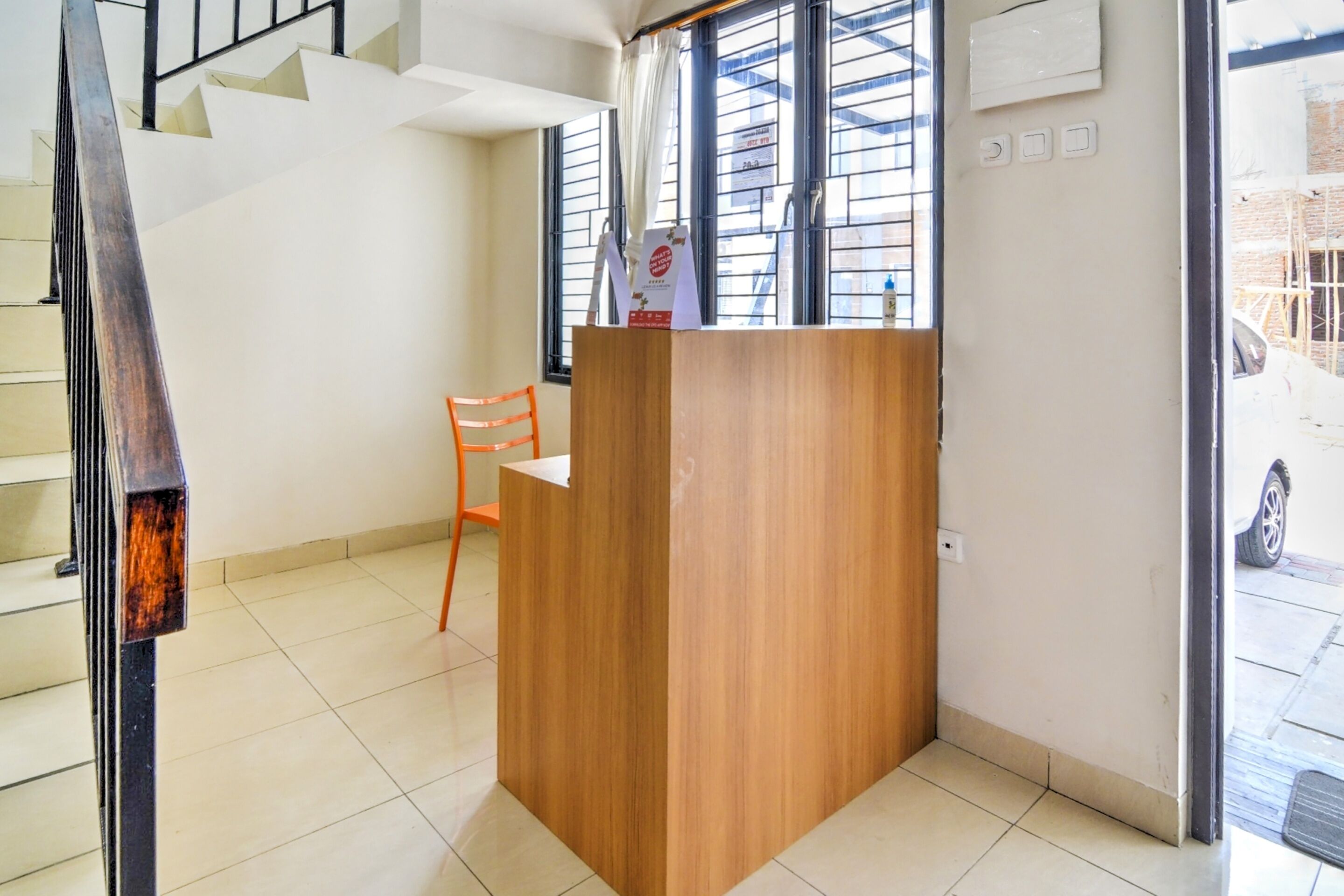 A reception area with a wooden desk, a chair, and a staircase.