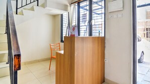 A reception area with a wooden desk, a chair, and a staircase. - OYO 3346 Rukos Colombus G5 (Karawang)