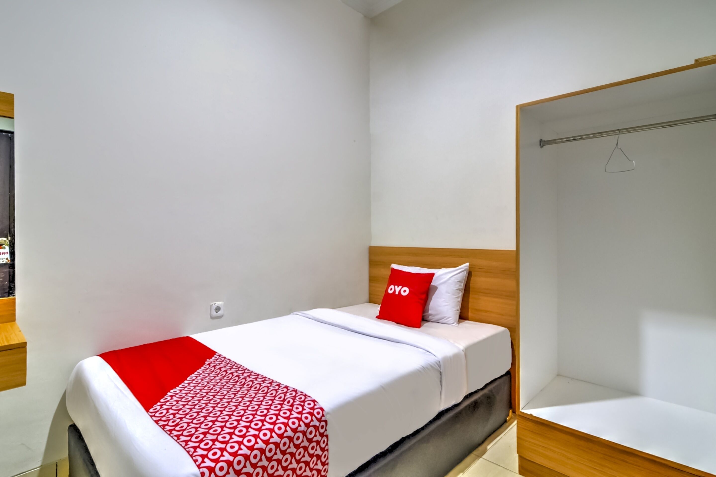 A small, neatly arranged bedroom with a bed, a wooden headboard, and a wardrobe.