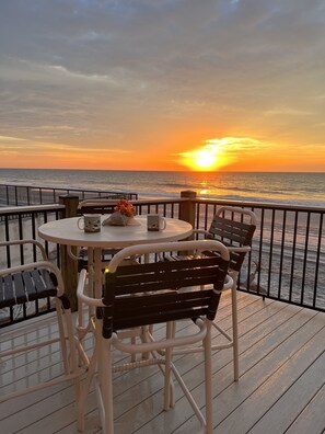 A deck with a round table and chairs, overlooking the ocean at sunset. - Direct Ocean Front! Beautiful Cabana End Unit GROUND FLOOR...rare find! (Murrells Inlet)