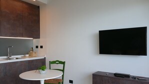 A modern kitchen with a built-in TV, a dining table with chairs, and a small plant on the table. - Beautiful apartment for 3 guests with WIFI and terrace (Ventimiglia)