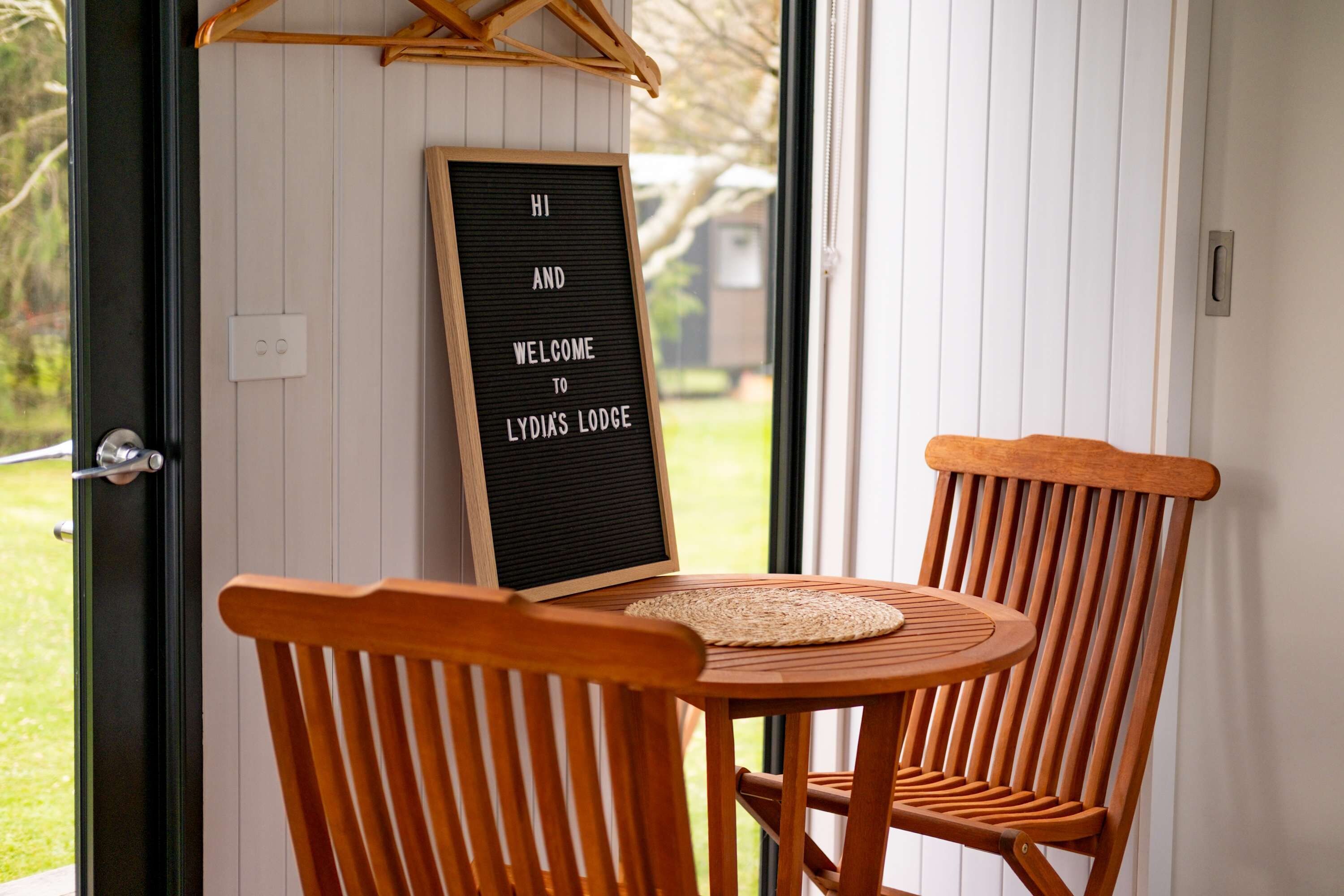A wooden chair and table with a welcome sign at Lydia's Lodge.